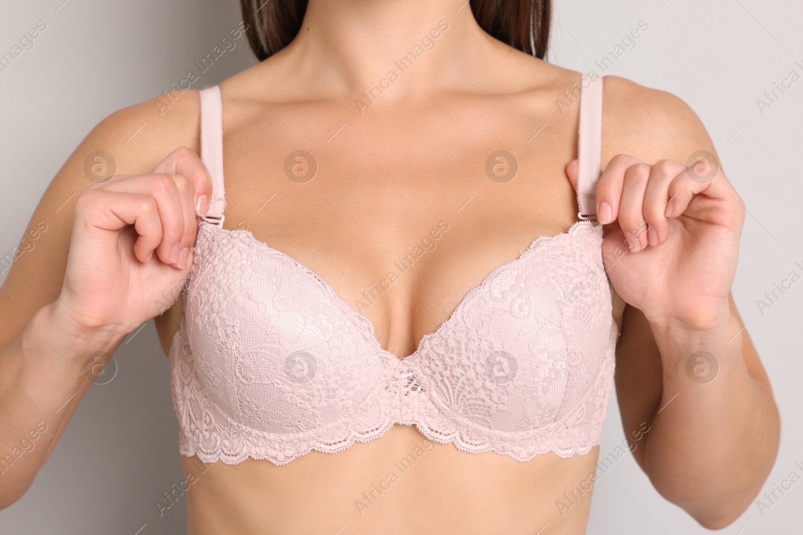 Woman wearing beautiful pink bra on light grey background, closeup Photo of Woman wearing beautiful pink bra on light grey background, closeup