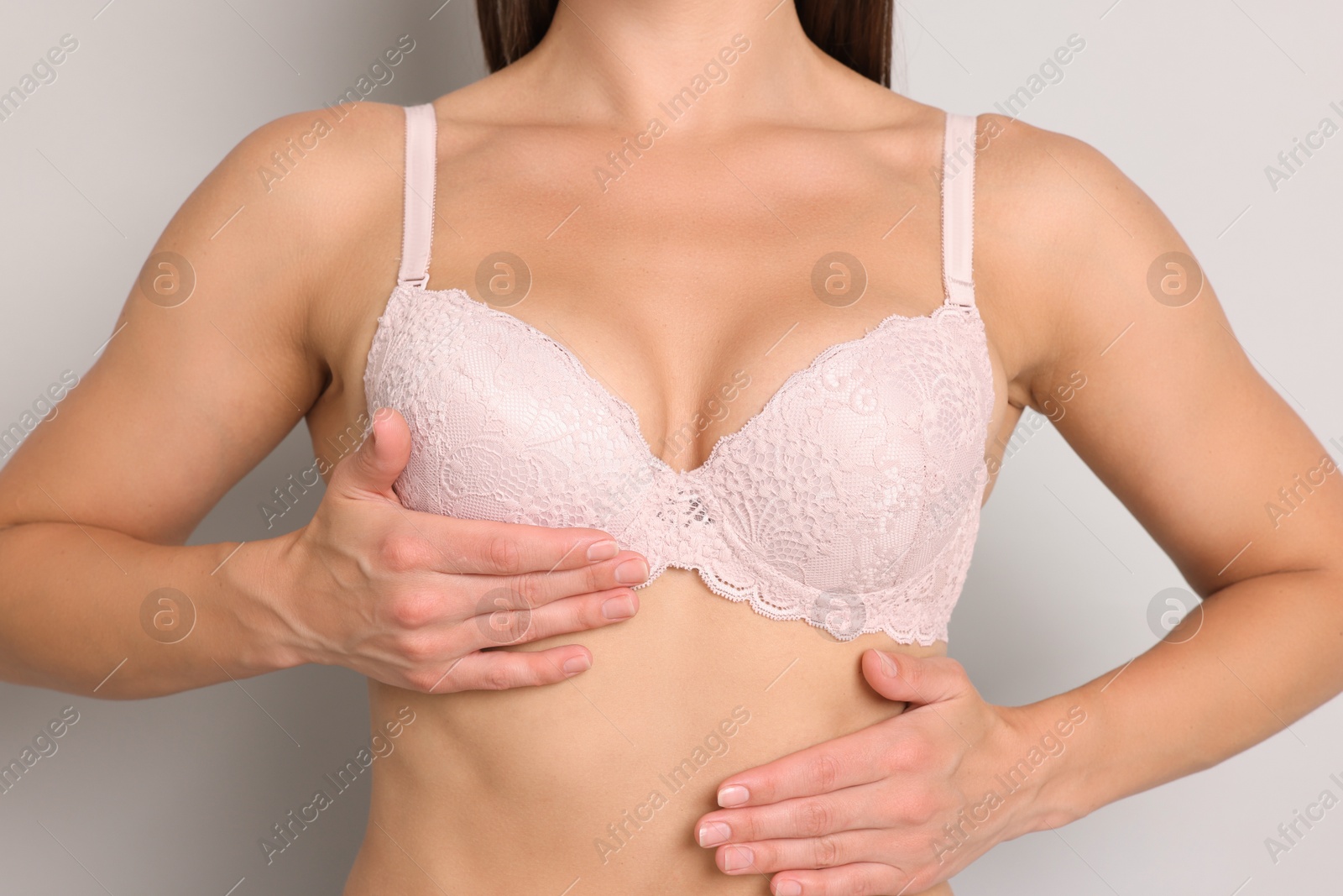 Woman wearing beautiful pink bra on light grey background, closeup Photo of Woman wearing beautiful pink bra on light grey background, closeup
