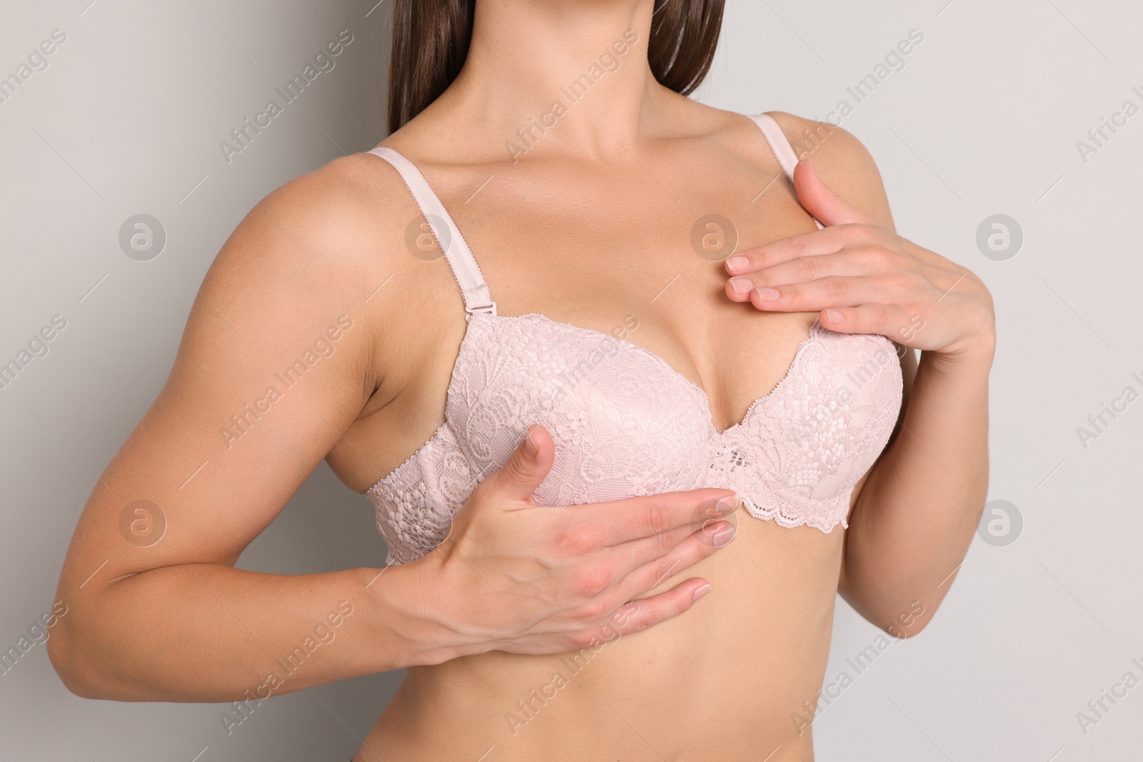 Woman wearing beautiful pink bra on light grey background, closeup Photo of Woman wearing beautiful pink bra on light grey background, closeup