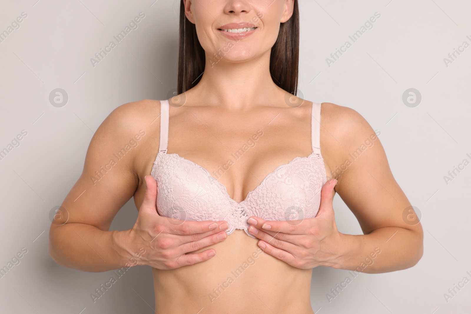 Woman wearing beautiful pink bra on light grey background, closeup Photo of Woman wearing beautiful pink bra on light grey background, closeup