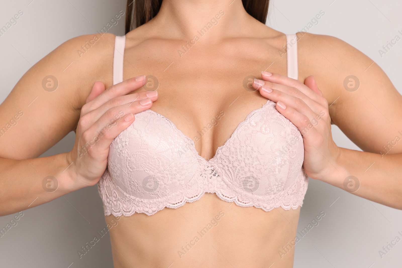 Woman wearing beautiful pink bra on light grey background, closeup Photo of Woman wearing beautiful pink bra on light grey background, closeup