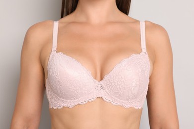 Photo of Woman wearing beautiful pink bra on light grey background, closeup