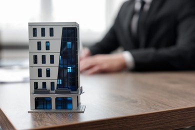 Photo of Real estate agent working at desk in office, focus on house model