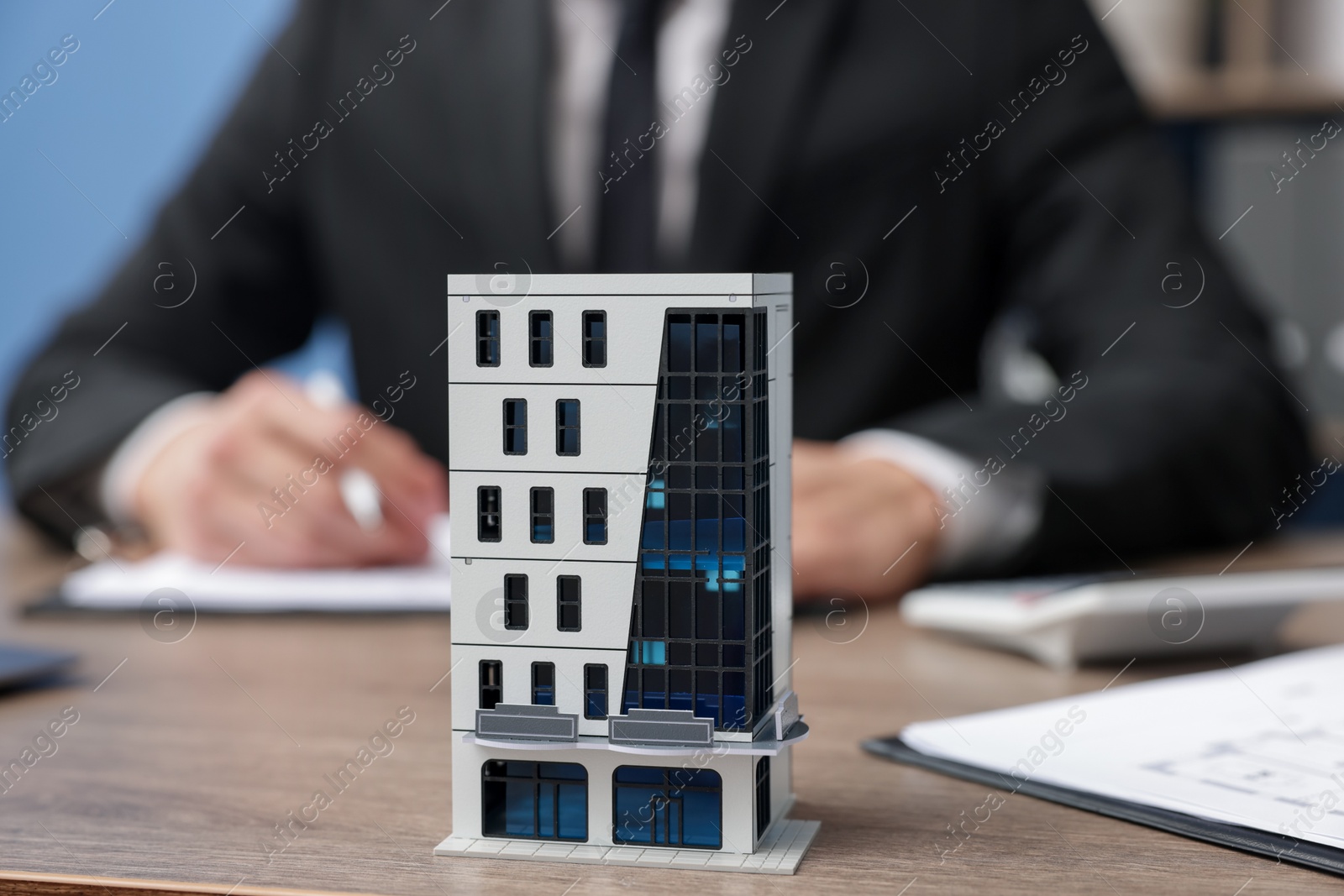 Photo of Real estate agent working at desk in office, focus on house model