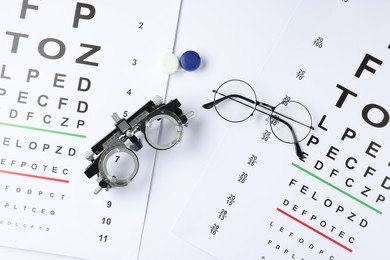 Photo of Vision test charts, glasses, trial frame and lenses on white background, flat lay
