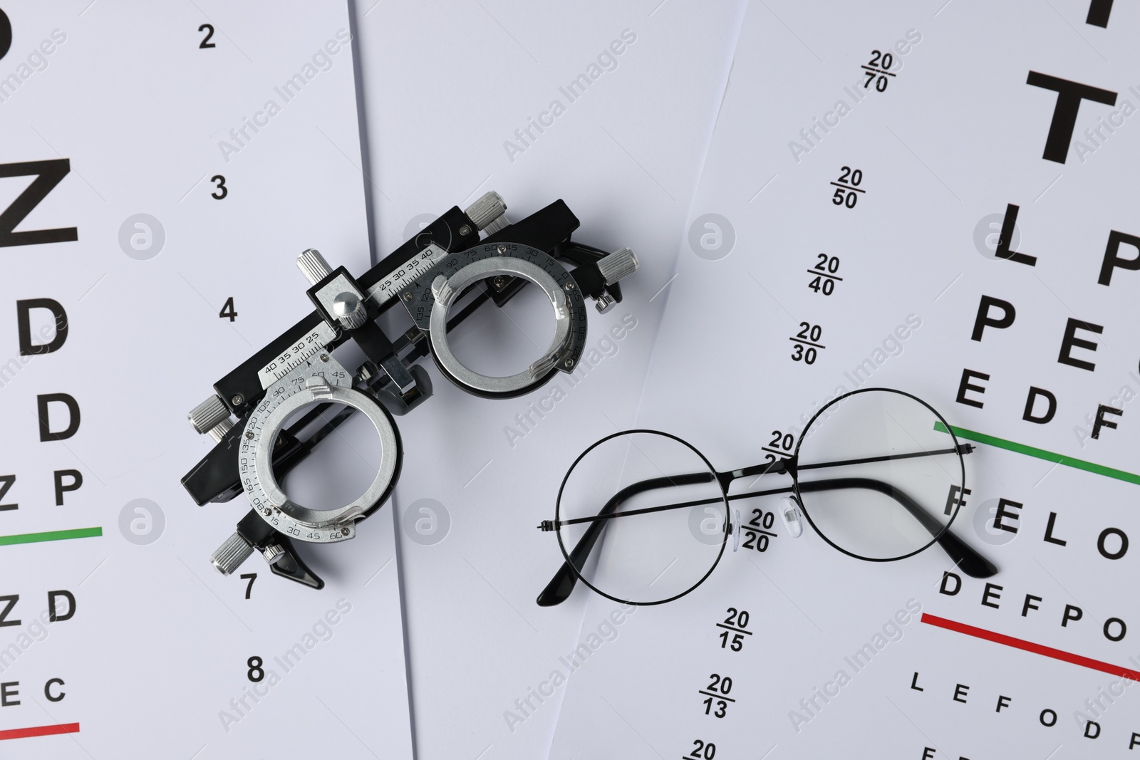 Vision test charts, glasses and trial frame on white background, flat lay Photo of Vision test charts, glasses and trial frame on white background, flat lay