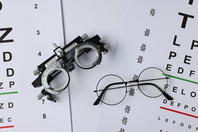 Photo of Vision test charts, glasses and trial frame on white background, flat lay