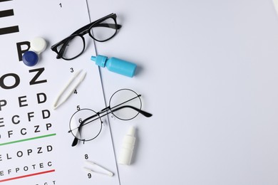 Photo of Vision test chart, glasses, tweezers, bottles of medical drops and lenses on white background, flat lay. Space for text