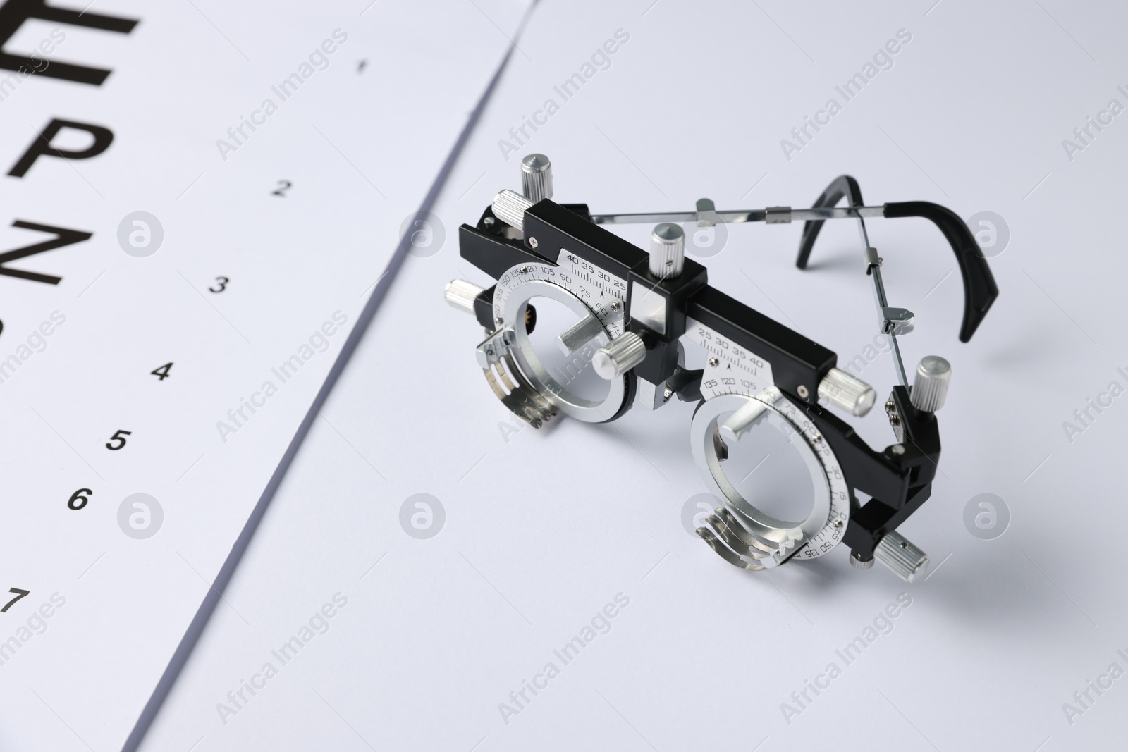 Trial frame and vision test chart on white background, closeup Photo of Trial frame and vision test chart on white background, closeup