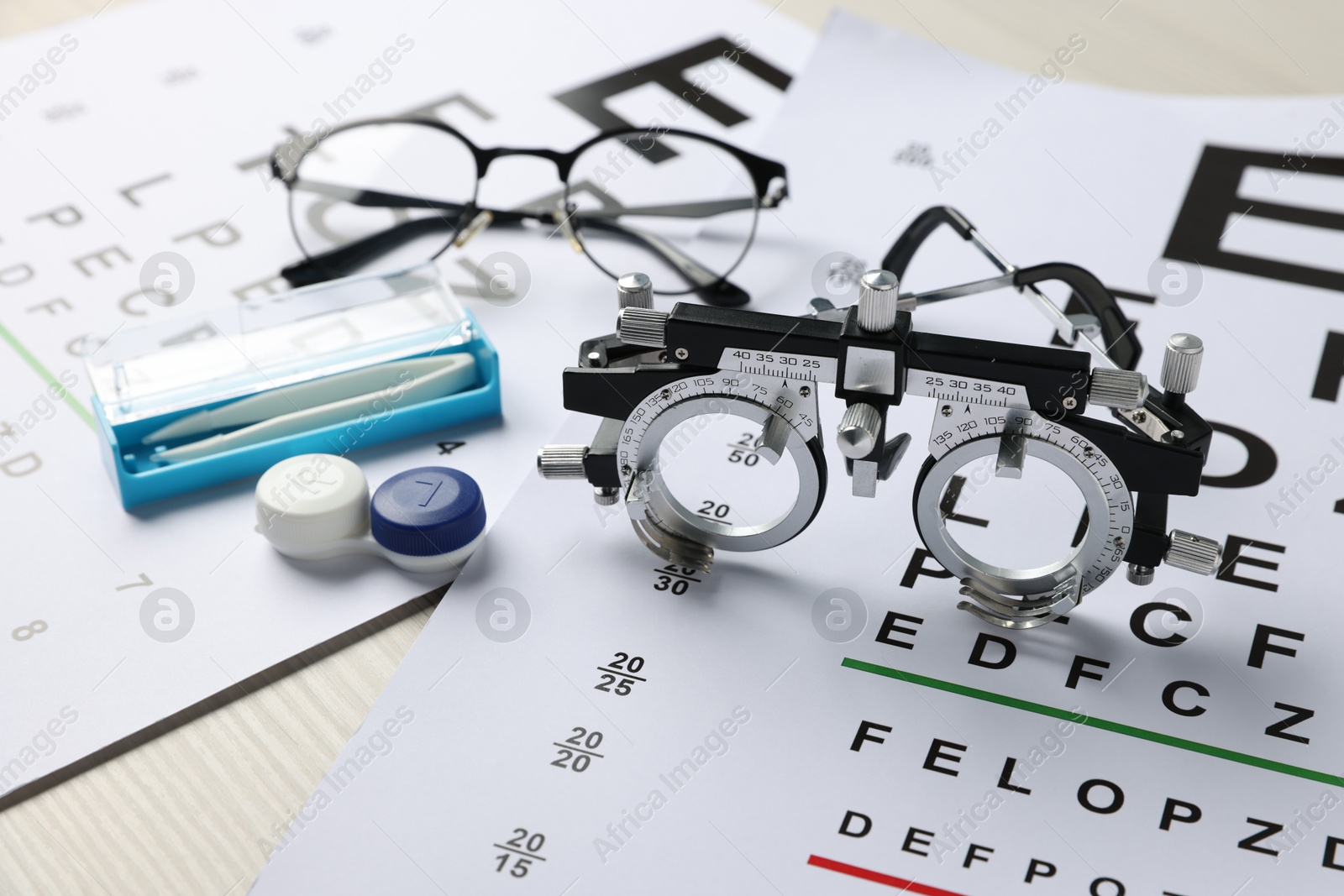 Vision test charts, trial frame, glasses, tweezers and lenses on table, closeup Photo of Vision test charts, trial frame, glasses, tweezers and lenses on table, closeup