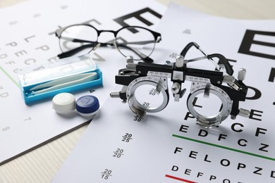 Photo of Vision test charts, trial frame, glasses, tweezers and lenses on table, closeup