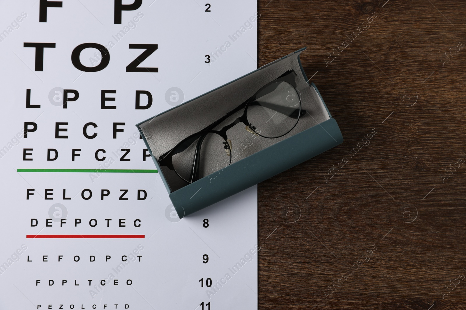 Vision test chart, glasses and case on wooden table, top view Photo of Vision test chart, glasses and case on wooden table, top view