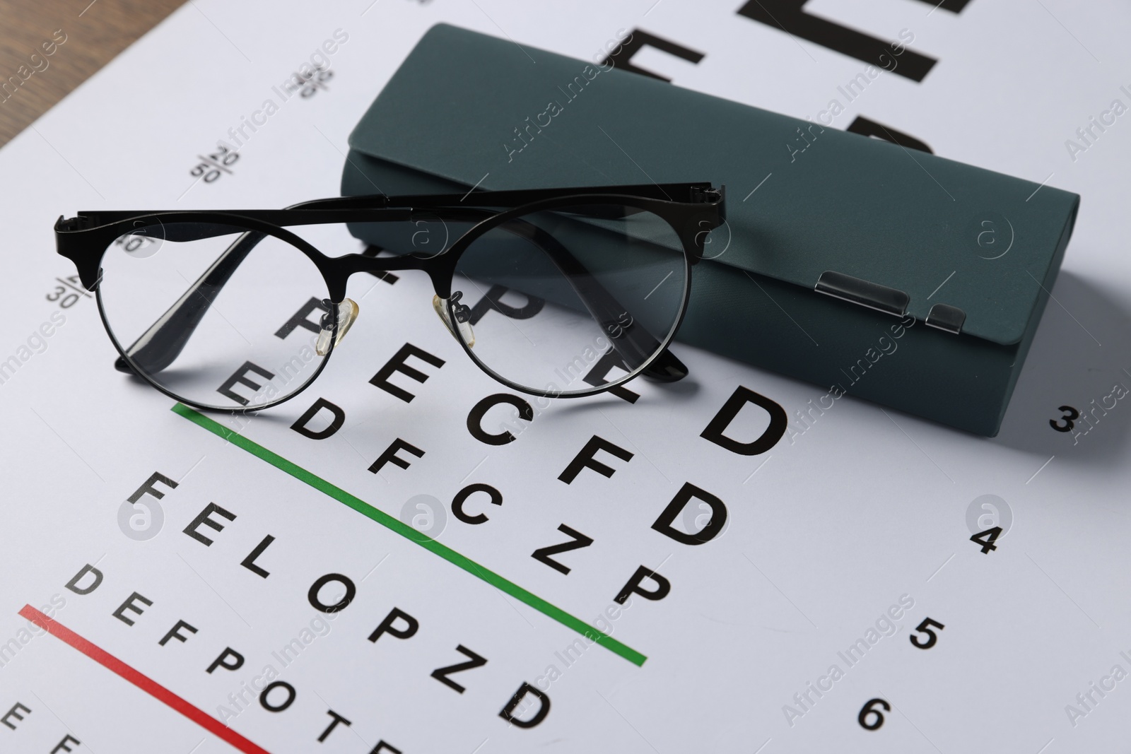 Vision test chart, glasses and case on table, closeup Photo of Vision test chart, glasses and case on table, closeup