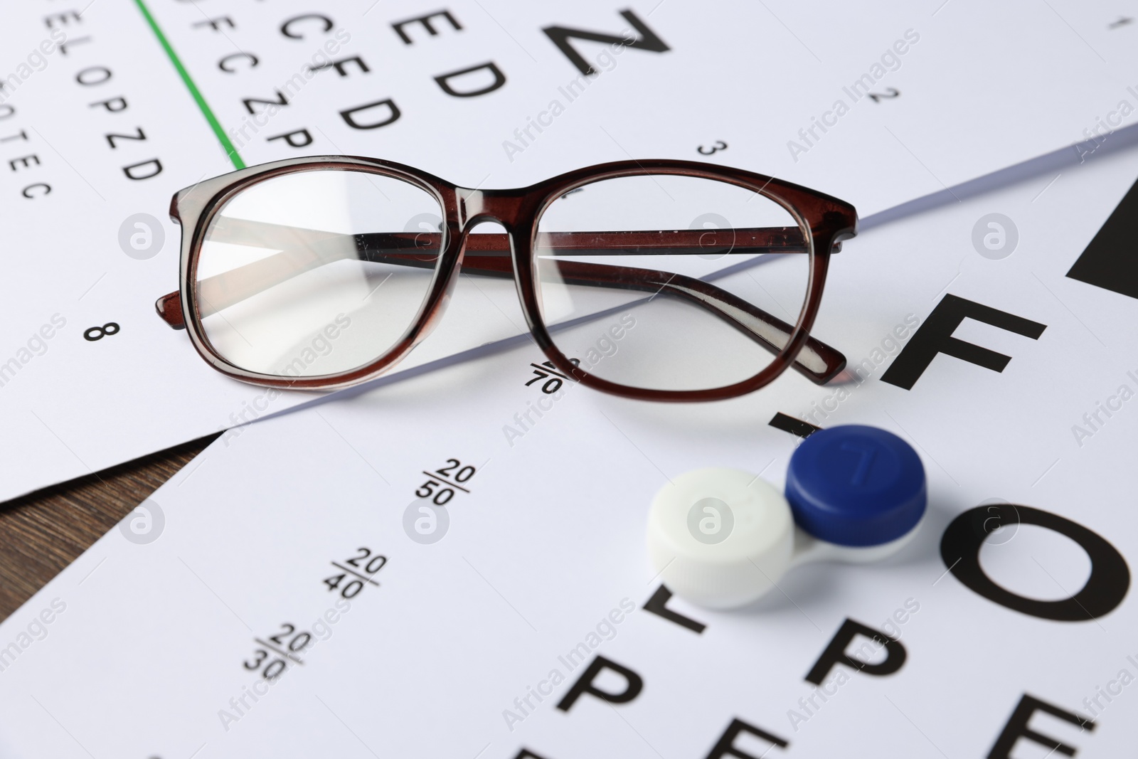 Photo of Vision test charts, lenses and glasses on table, closeup