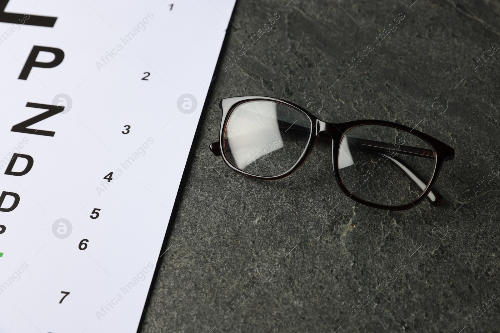 Vision test chart and glasses on grey table, closeup Photo of Vision test chart and glasses on grey table, closeup