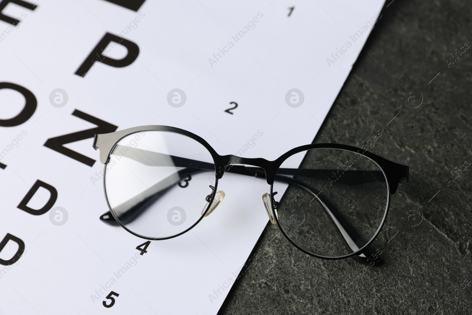 Vision test chart and glasses on grey table, above view Photo of Vision test chart and glasses on grey table, above view