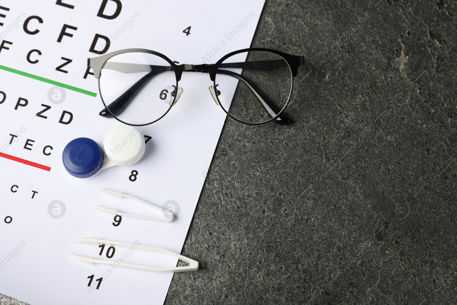 Vision test chart, glasses, tweezers and lenses on grey table, flat lay. Space for text Photo of Vision test chart, glasses, tweezers and lenses on grey table, flat lay. Space for text