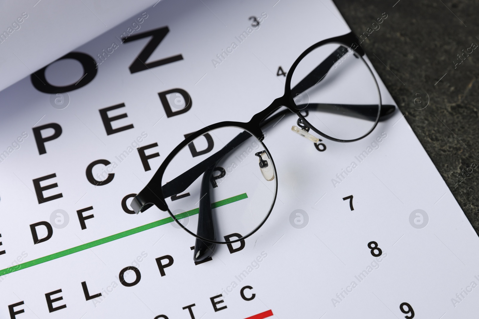 Vision test chart and glasses on grey table, above view Photo of Vision test chart and glasses on grey table, above view