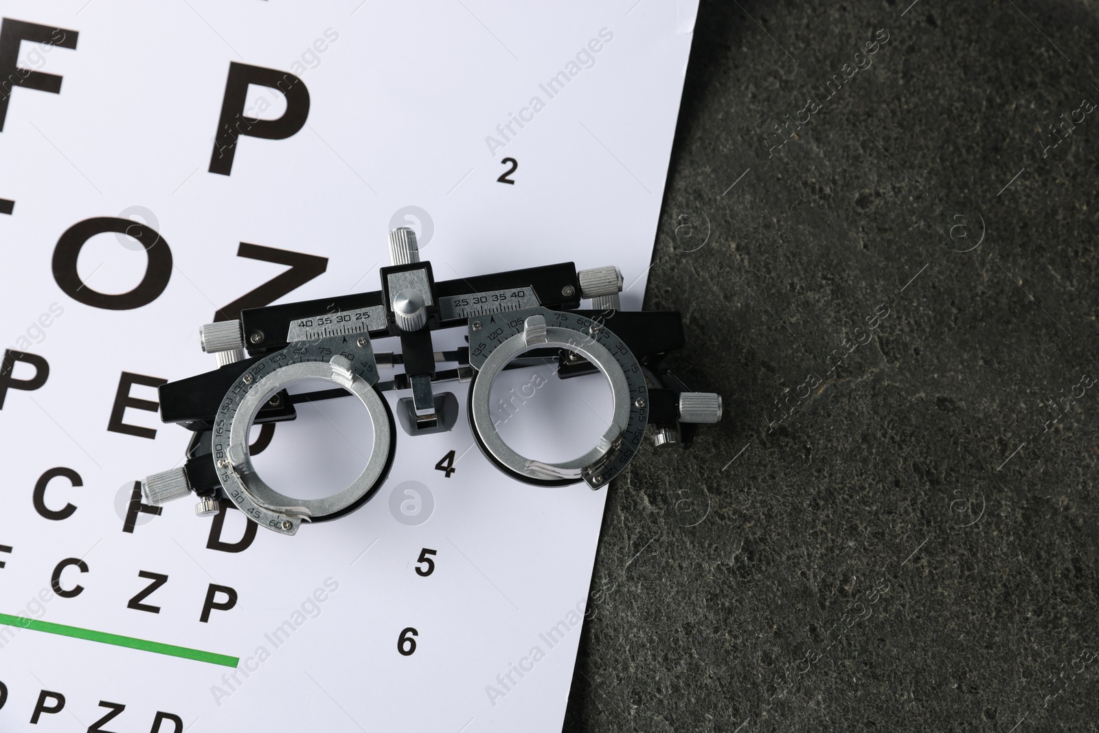 Vision test chart and trial frame on grey table, top view. Space for text Photo of Vision test chart and trial frame on grey table, top view. Space for text
