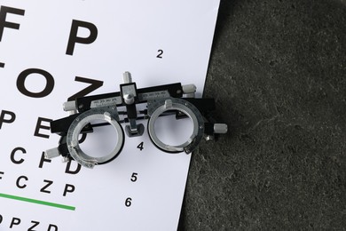 Photo of Vision test chart and trial frame on grey table, top view. Space for text