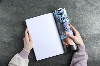 Photo of Woman reading magazine at grey table, top view. Mockup for design