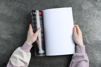 Photo of Woman reading magazine at grey table, top view. Mockup for design