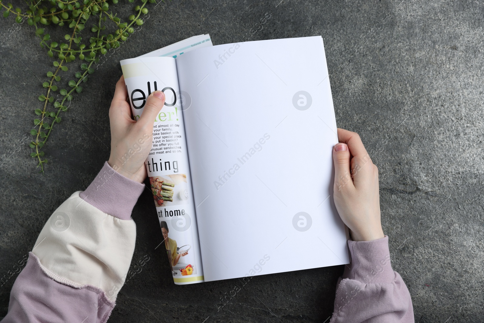 Photo of Woman reading magazine at grey table, top view. Mockup for design