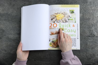 Photo of Woman reading magazine at grey table, top view. Mockup for design
