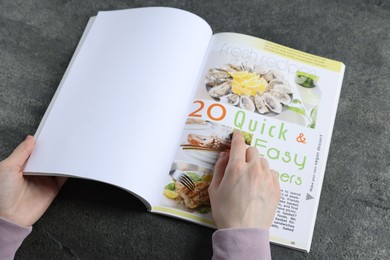 Photo of Woman reading magazine at grey table, closeup. Mockup for design