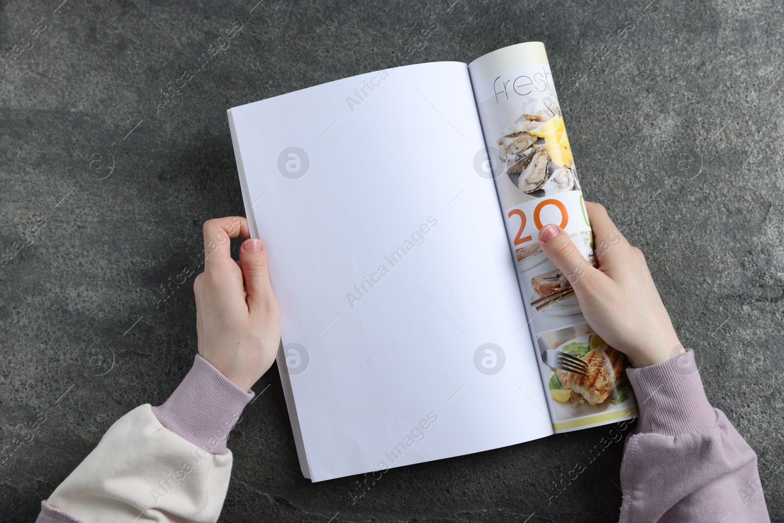Woman reading magazine at grey table, top view. Mockup for design Photo of Woman reading magazine at grey table, top view. Mockup for design