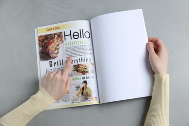 Photo of Woman reading magazine at light grey table, top view. Mockup for design