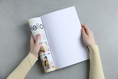 Photo of Woman reading magazine at light grey table, top view. Mockup for design