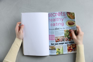 Photo of Woman reading magazine at light grey table, top view. Mockup for design