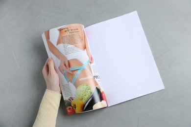 Photo of Woman reading magazine at light grey table, top view. Mockup for design
