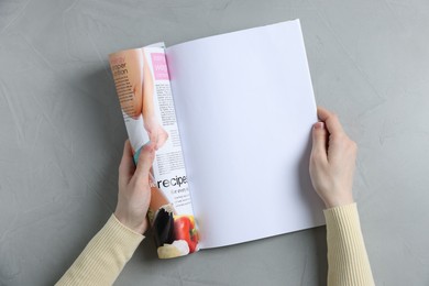 Photo of Woman reading magazine at light grey table, top view. Mockup for design