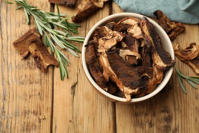 Photo of Dried chanterelle mushrooms with rosemary on wooden table, flat lay