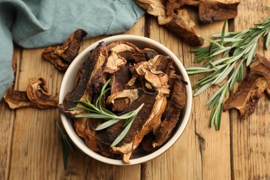 Photo of Dried chanterelle mushrooms with rosemary on wooden table, flat lay