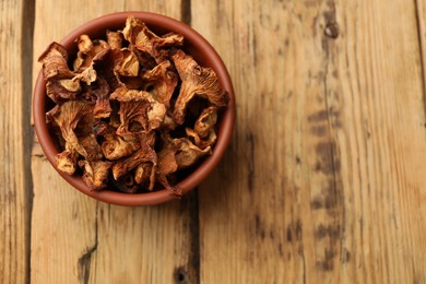 Photo of Dried chanterelle mushrooms on wooden table, top view. Space for text