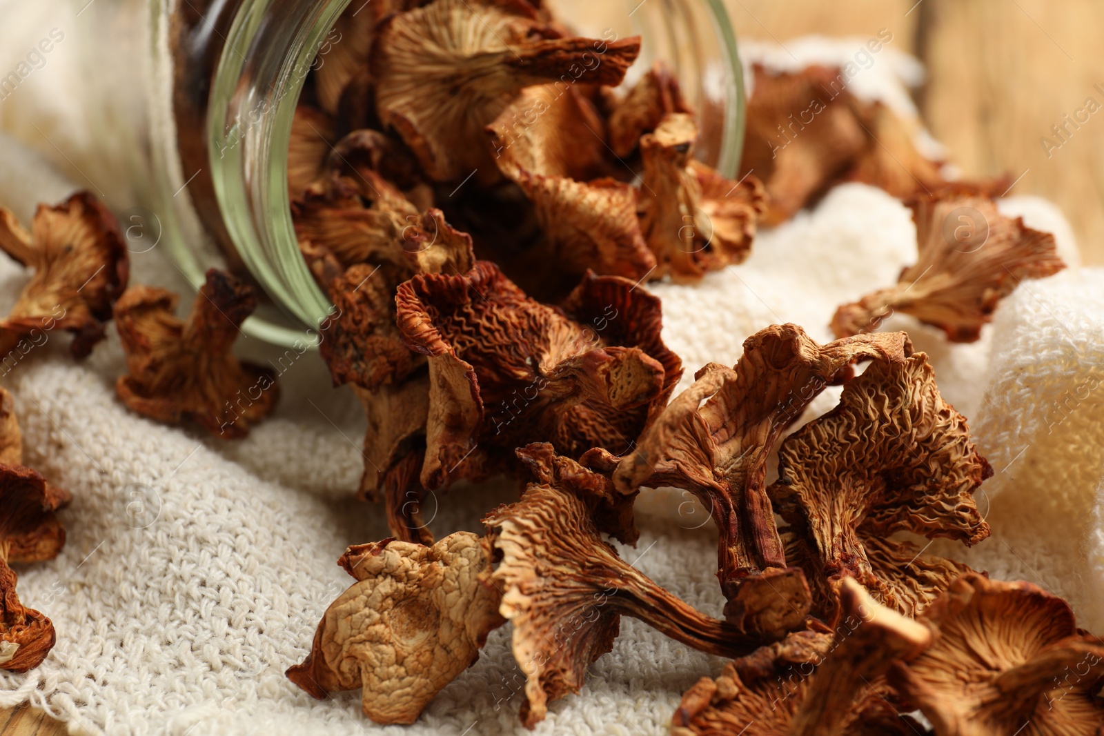 Dried chanterelle mushrooms in jar and towel on wooden table, closeup Photo of Dried chanterelle mushrooms in jar and towel on wooden table, closeup