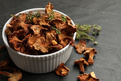 Photo of Dried chanterelle mushrooms with thyme on black table, closeup