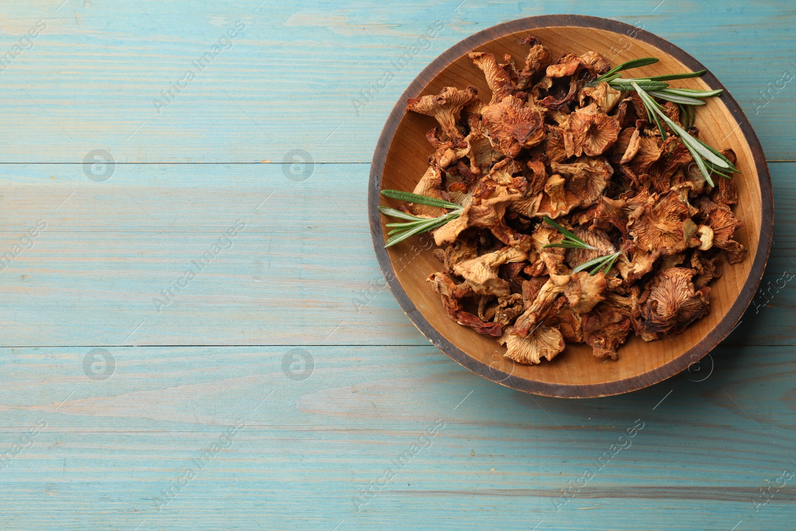 Dried chanterelle mushrooms with rosemary on blue wooden table, top view. Space for text Photo of Dried chanterelle mushrooms with rosemary on blue wooden table, top view. Space for text