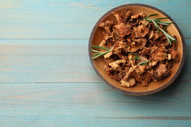 Photo of Dried chanterelle mushrooms with rosemary on blue wooden table, top view. Space for text