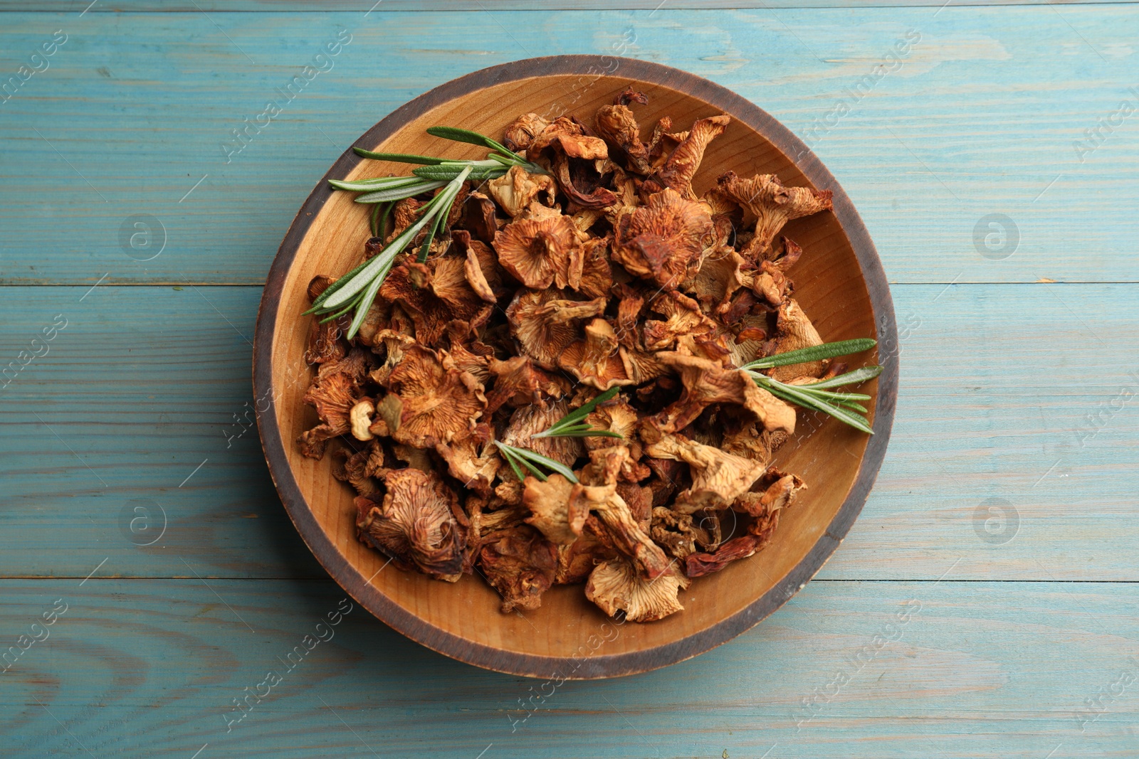 Dried chanterelle mushrooms with rosemary on blue wooden table, top view Photo of Dried chanterelle mushrooms with rosemary on blue wooden table, top view
