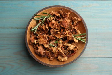 Photo of Dried chanterelle mushrooms with rosemary on blue wooden table, top view