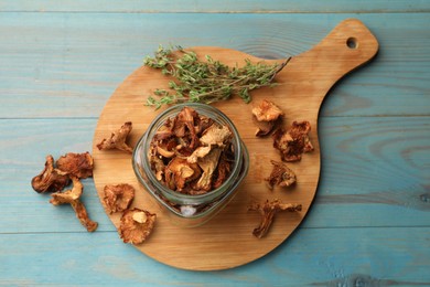 Photo of Dried chanterelle mushrooms with thyme on blue wooden table, top view