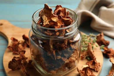 Photo of Dried chanterelle mushrooms with thyme on blue wooden table, closeup
