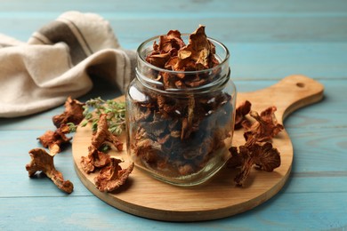 Photo of Dried chanterelle mushrooms with thyme on blue wooden table