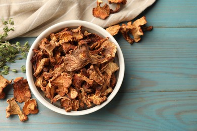 Photo of Dried chanterelle mushrooms with thyme on blue wooden table, flat lay. Space for text