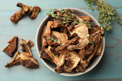 Photo of Dried chanterelle mushrooms with thyme on blue wooden table, flat lay