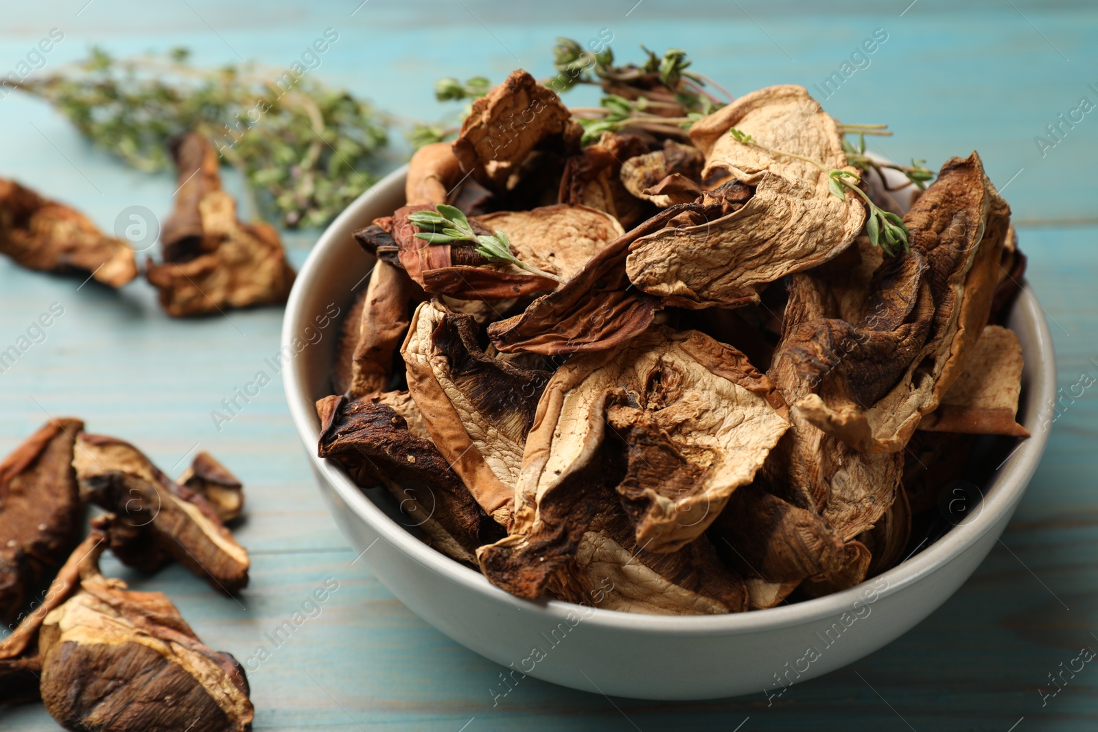 Photo of Dried chanterelle mushrooms with thyme on blue wooden table, closeup